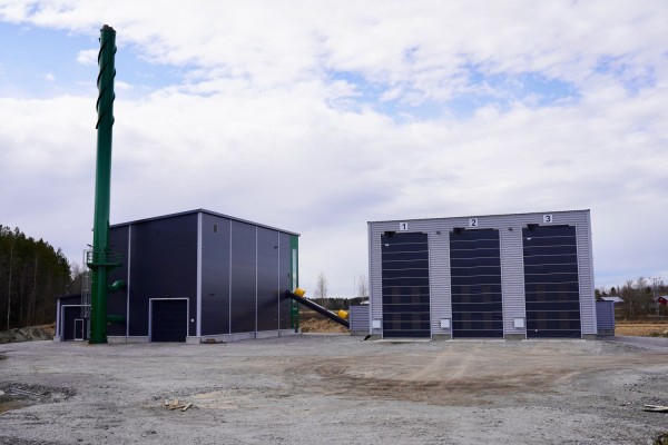 Pedersöre värmes värmecentral i Bennäs. Två byggnader. Den ena har en hög skorsten. Den andra har tre höga dörrar.