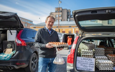 Thomas Snellman Pietarsaaren torilla. Hänellä on muna munatarjottimen kädessään. Taustalla on auto.