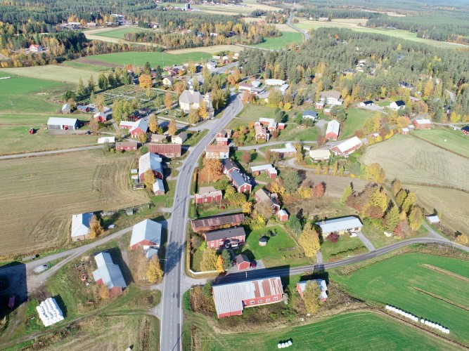 En flygbild över Sisbacka. Kyrkan, landsvägen och byggnader.