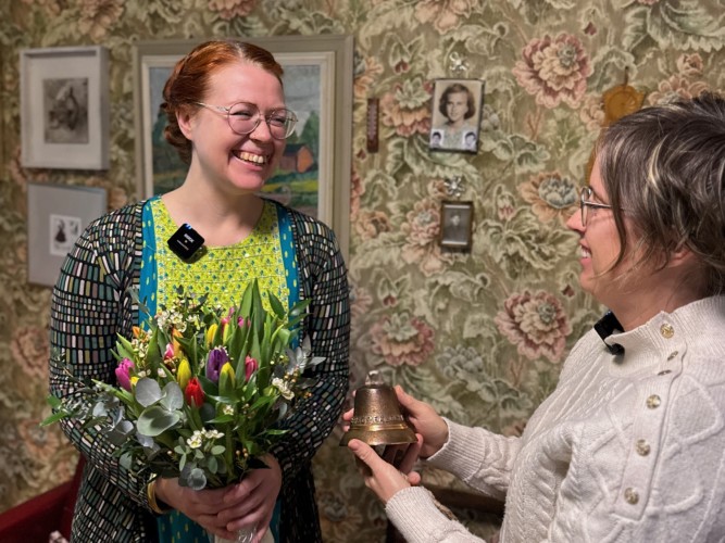 Charlotta Kerbs tar emot kulturpriset, en vällingklocka. Hon har en blombukett i handen.