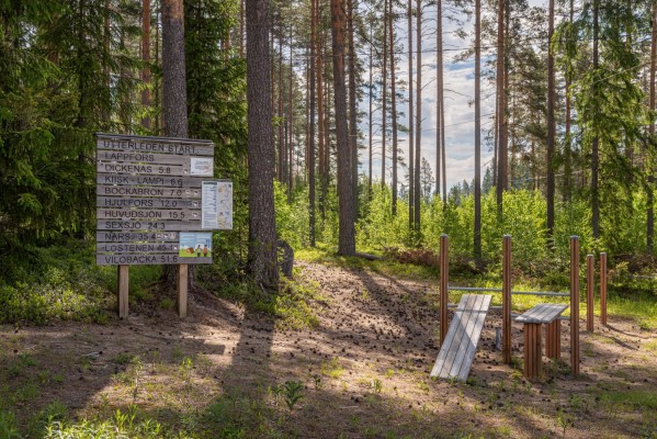 Informationstavla med sträckor till olika deletappen av Utterleden. Ett utegym.