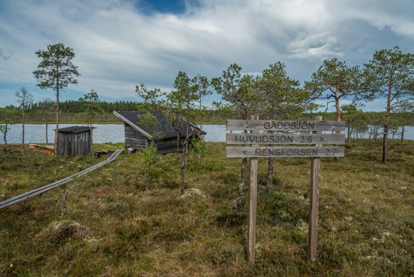 Kuva Gäddsjön-järvestä jossa näkyy laavu, kyltti ja järvi.