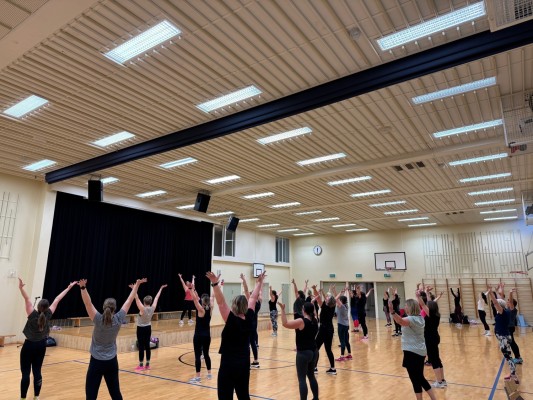 Bild av en grupp med människor som står med händerna uppsträckta i luften. 