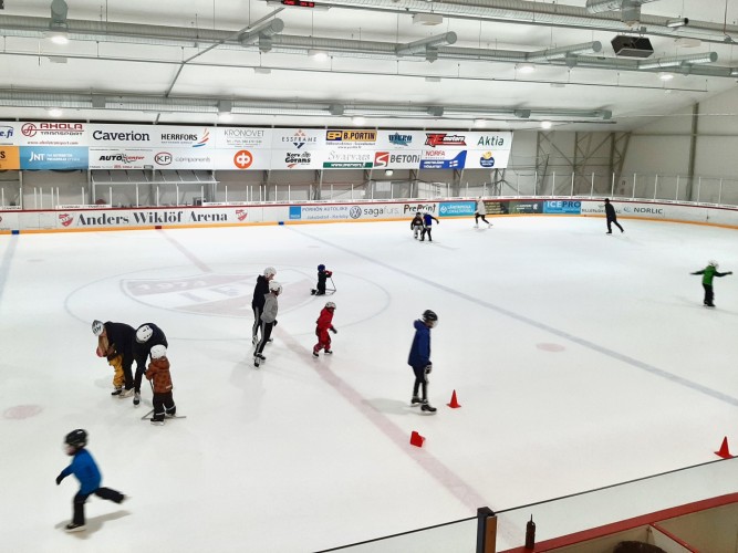Barn och vuxna skrinnar i en ishall. Inga hockeyspelare.