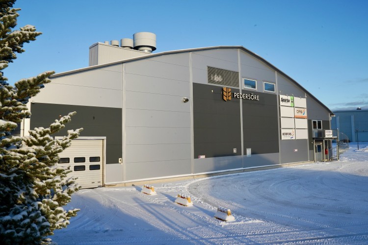 Ishallen fotograferad från parkeringen, med reklamskylt. Det är lite snö på marken.