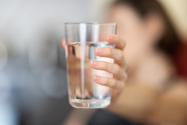 En hand håller i ett glas med vatten.