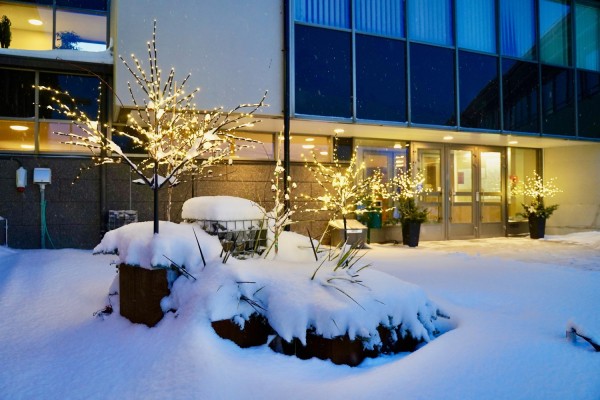 Kommungårdens entré är intäkt i vit snö. Julbelysningen lyser.
