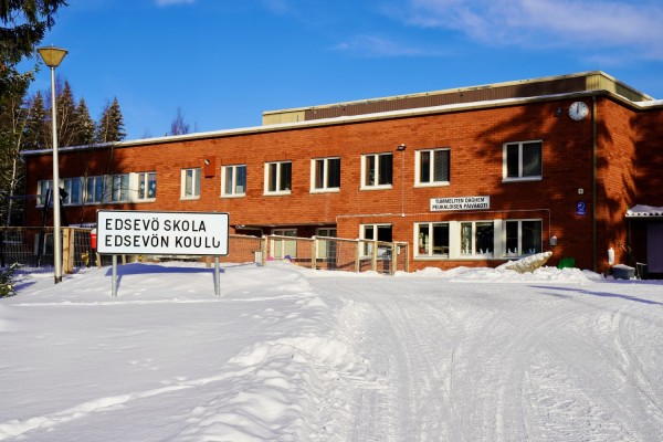 Edsevö skola fotograferad en vacker vinterdag. Längst fram i bild en skylt med texten "Edsevö skola / Edsevön koulu".