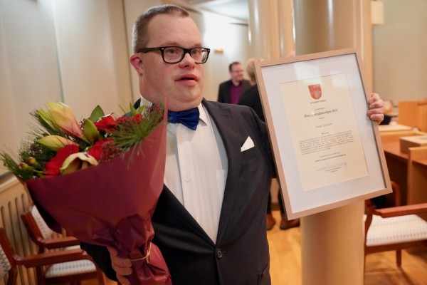 Fjolårets pristagare Jonas Jansson med blommor och diplom i hand.