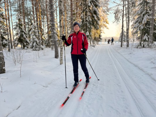 Nainen hiihtää hiihtoladulla metsässä.