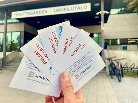 En hand håller upp fem simbiljetter utanför simhallen i Jakobstad.