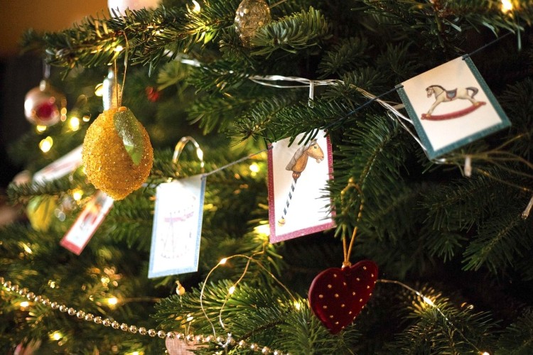 Närbild på dekoration i en julgran. Pappersflaggor och bollar och glitter.