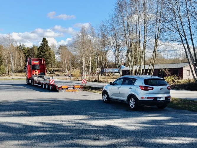 Kadulle pysäköity auto. Taustalla näkyy kuorma-auto perävaunineen.