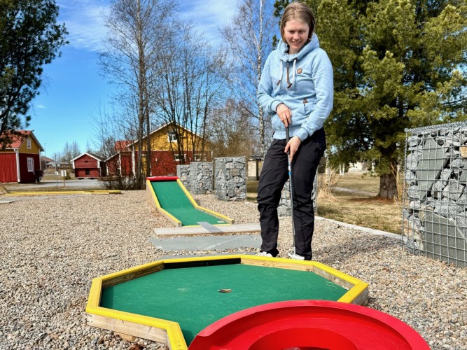 En kvinna spelar minigolf.