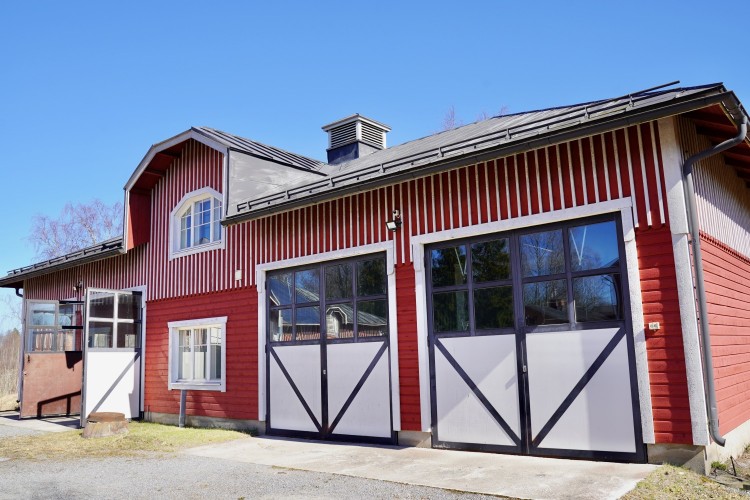 Byggnaden där mopedverkstaden öppnar. Ett rött hus med tre dubbeldörrar.