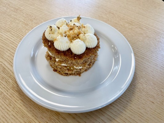 Bakelsen morotskaka med anis-kinuskisås och cheesecakefrosting. Brunfärgad bakselse med gräddvita bollar i topp.