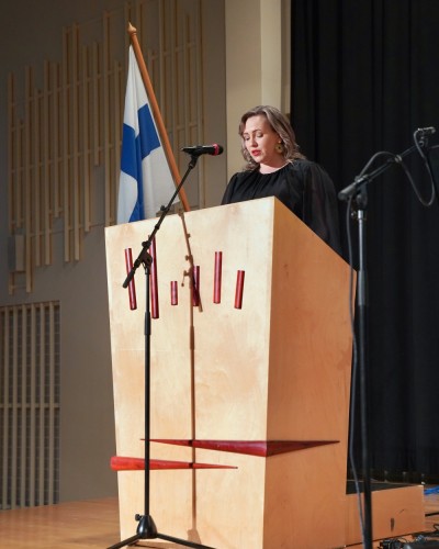 En kvinna håller tal från talarstol på scenen.