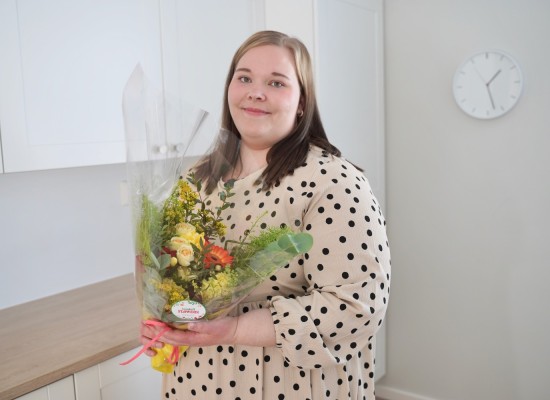 Voittaja Ulrica Tupeli on kotonaan keittiössään kukkakimppu sylissään.
