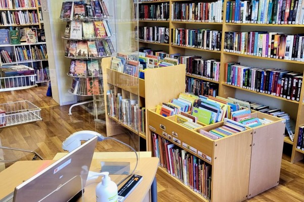 Bibliotekshyllor och böcker samt en lånedisk. Lappfors utlåningsstation.