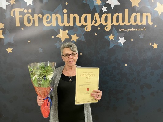 Palkinnonsaaja Carina Rönnlund, jolla on kukkia ja diplomi käsissään.
