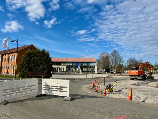 Korsningen mellan Mjölvägen och Skrufvilagatan. Vita staket som signalerar om avstängningen, och en grävmaskin vid vägkanten. I bakgrunden syns kommungården.