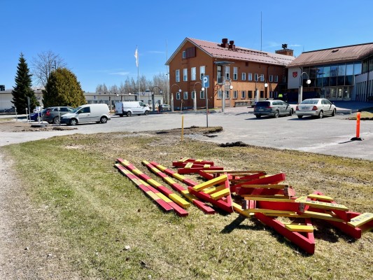 Kunnantalo etupihan pysäköintialue. Nurmikolla on puomeja, joiden avulla tullaan osoittaa suljettu parkkialue. Taustalla kunnantalo.