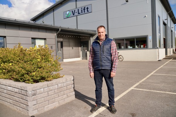 Toimitusjohtaja Mikael Vikström seisoo yrityksen toimiston edessä. Taustalla näkyy kyltti, jossa lukee V-Lift.