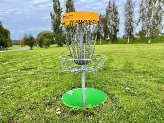 En frisbeegolfkorg på en gräsplan.