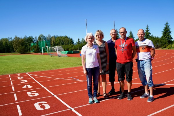 Funktionärer inom IK Falken poserar på sportplanen i Bennäs. En kvinna och fyra män.