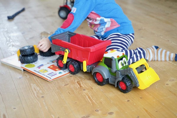 Ett barn leker med en plast traktor