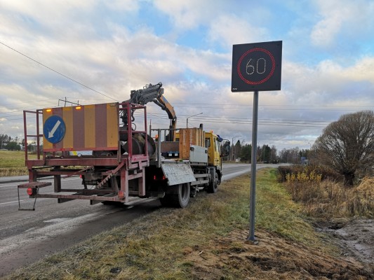 Muuttuva nopeusrajoitustaulu maantien varrella. Kuvassa myös kuorma-auto.