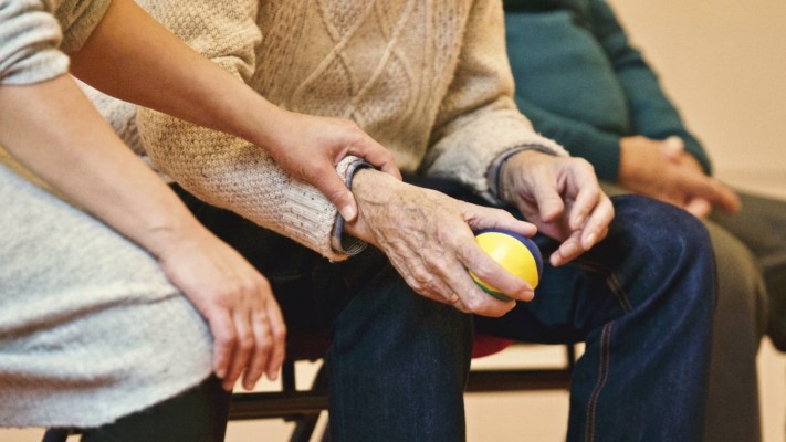 En äldre och en yngre persons händer i närbild.  De äldre håller i en boll.