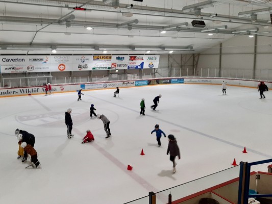 Bild inifrån ishallen AW Arena i Bennäs. På isen skrinnar barn omkring med några vuxna.
