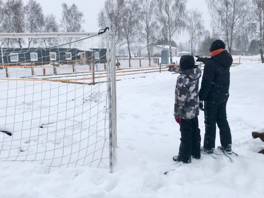 Två elever står på en snöig skolgård och pekar mot skolgården.