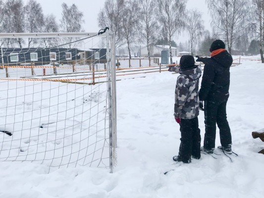 Kaksi oppilasta seisovat koulupihalla. He osoittavat kättään kohti pihalla olevaa kiinteistöä.