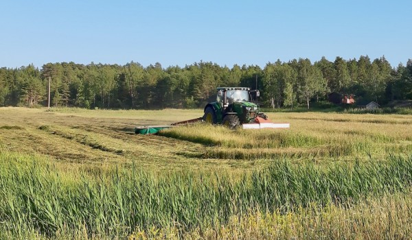 En traktor kör på en åker med en skördare efter sig.