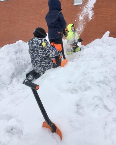 Kolme lasta kaivaa lumessa.