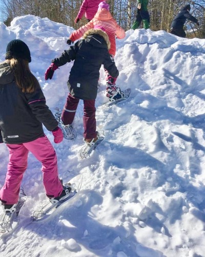Lapset kävelevät lumella lumikengillä.
