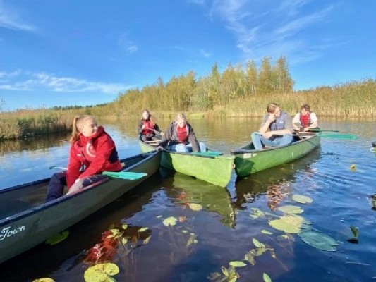 Ungdomar sitter i kanoter på en sjö. 