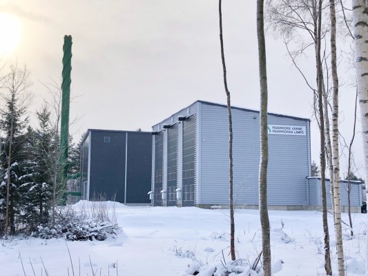 Suuri biolämpölaitos Pännäisissä. Kaksi suurta hallia, joilla suuret, korkeat ovet, ja korkea savupiippu.