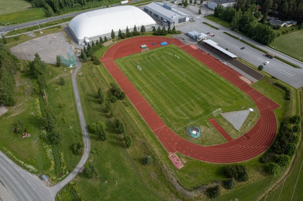 Pedersören urheilukeskus Pännäisissä kuvattuna droonilla. Juoksuradut, jalkapallokenttä, katsomo, jäähalli ja palloiluhalli näkyvät.