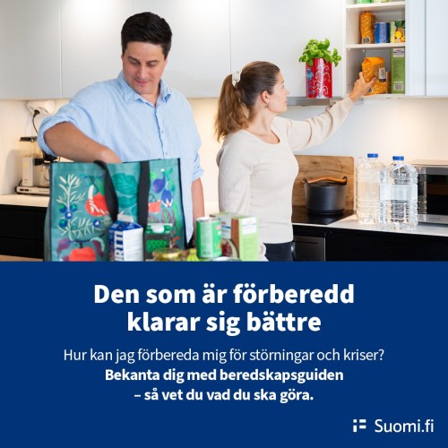 En man och en kvinna plockar in matvaror i skåpet.