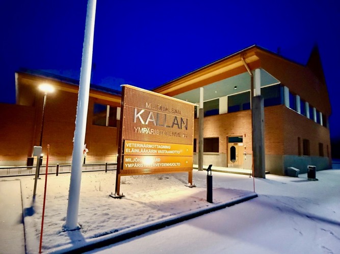 Miljöhälsan Kallans nya hus i decembermörker, upplyst fasad, mörkblå himmel.