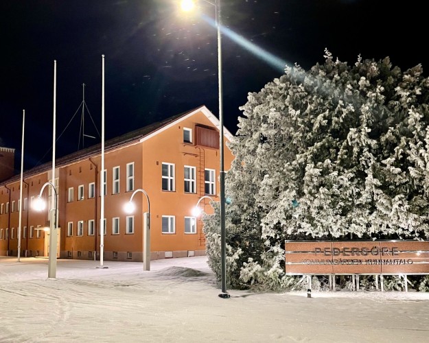 Kvällsbild av kommungården. Svart himmel, lampor som lyser upp kommungården.