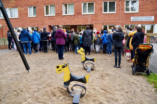 Daghemmets utegård med invigningens deltagare i bakgrunden.