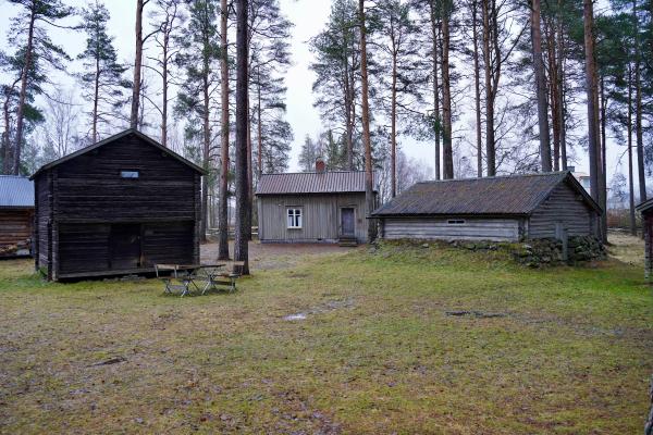 Kolme vanhaa rakennusta museoalueella. Keskellä hirsimökki.