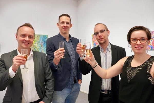 Fyra festklädda personer höjer sina champagneglas.