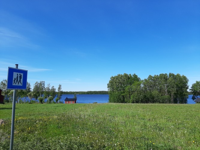 Sjö, vandringsledsskylt och äng